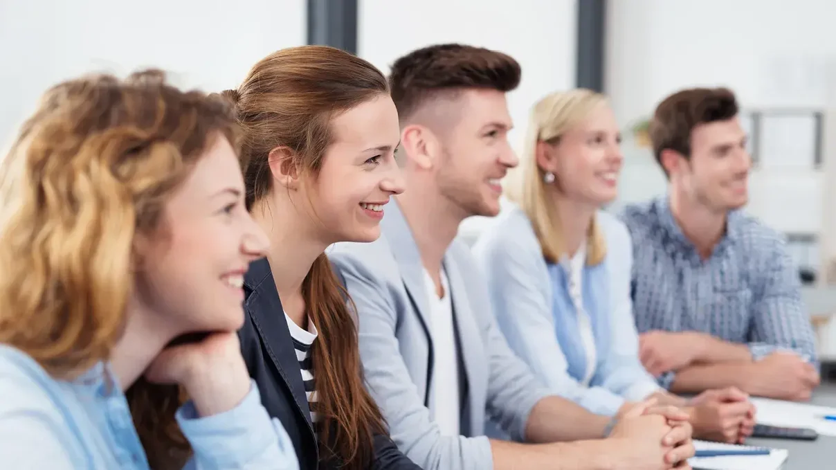 Fünf Personen sitzen an einem Tisch in einem Seminar
